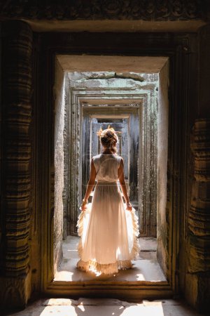Photo for Beautiful young woman wearing white robe dress in ancient Khmer ruins, Angkor Wat - Royalty Free Image