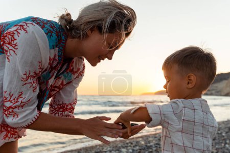 Téléchargez les photos : Mère et son mignon petit fils ramassant des cailloux sur la plage de galets. - en image libre de droit