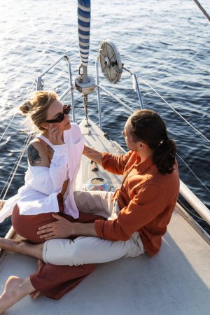 Téléchargez les photos : Jeune couple séduisant se détendre sur le voilier pendant la voile dans la mer. - en image libre de droit
