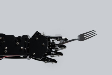 Foto de Mano de robot real con tenedor. Concepto de desarrollo de IA y automatización robótica de procesos. - Imagen libre de derechos