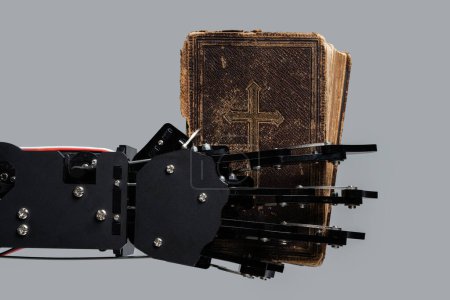 Foto de Mano de robot real con libro bíblico antiguo. Conceptos de desarrollo de inteligencia artificial y aprendizaje automático. - Imagen libre de derechos