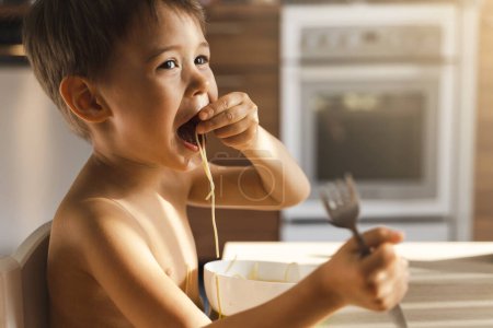 Foto de Niño lindo comiendo su comida favorita - Spaghetti. - Imagen libre de derechos