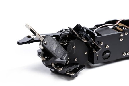 Téléchargez les photos : Véritable main robotique avec clé de voiture noire. Concept d'intelligence artificielle dans l'industrie des transports. - en image libre de droit