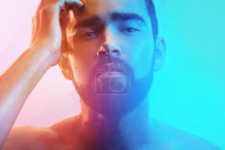 Téléchargez les photos : Portrait de beau jeune homme au visage mouillé en lumière bleue et orange - en image libre de droit