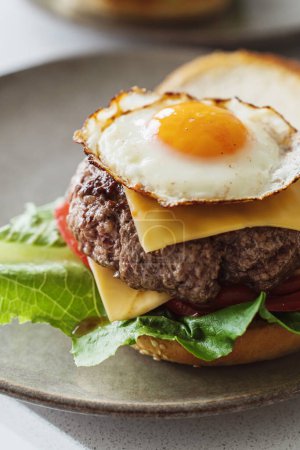 Foto de Deliciosa hamburguesa casera con queso adornada con un huevo soleado perfectamente frito. - Imagen libre de derechos