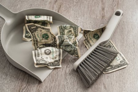 Photo for Dustpan and brush alongside scattered one-dollar bills on the floor. - Royalty Free Image