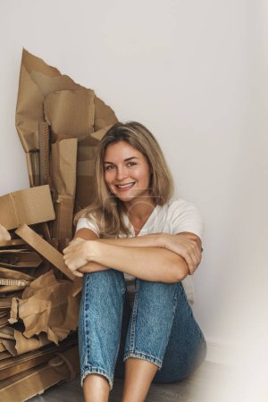 Foto de Joven mujer varita pila de residuos de cartón en casa. Conceptos de reciclado de papel y clasificación de residuos. - Imagen libre de derechos