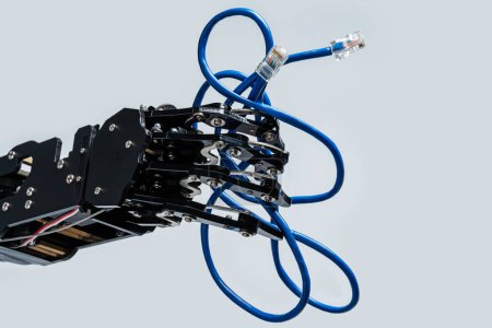 Foto de La mano del robot real sostiene el cable Ethernet azul con conector rj45 sobre fondo gris. - Imagen libre de derechos