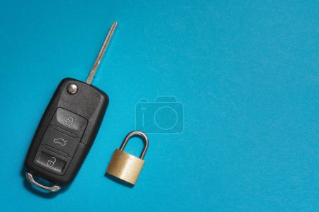Téléchargez les photos : Clé de voiture en plastique noir à côté d'un cadenas métallique jaune, avec espace de copie sur le côté droit - en image libre de droit