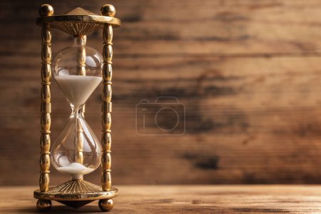 Photo for Golden hourglass on the wooden table with a wooden background - Royalty Free Image