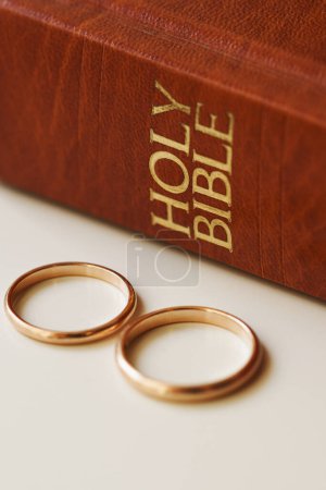 Téléchargez les photos : Gros plan de deux alliances d'or et d'une bible sainte représente le concept de mariage et l'amour entre deux chrétiens - en image libre de droit