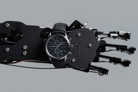 Téléchargez les photos : Véritable main robotique avec montre-bracelet. Concepts de gestion du temps ou rapidité du développement de l'IA. - en image libre de droit