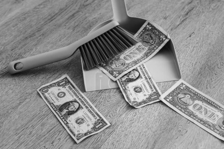 Foto de Sartén y cepillo junto a billetes dispersos de un dólar en el suelo. - Imagen libre de derechos