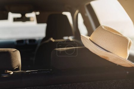 Téléchargez les photos : Chapeau à dessin repose sur le siège arrière d'une voiture garée sur la plage. - en image libre de droit