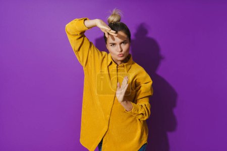 Téléchargez les photos : Portrait de jeune fille joyeuse portant chemise jaune dansant sur fond violet - en image libre de droit