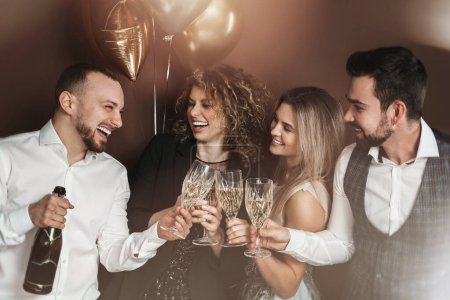 Foto de Grupo de personas elegantemente vestidas celebrando un día festivo o evento, bebiendo vino espumoso. - Imagen libre de derechos