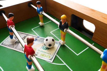 Photo for Table football game with US dollar bills scattered around it, alluding to a betting concept and victory - Royalty Free Image