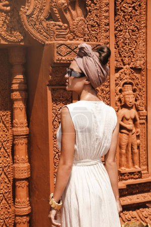 Photo for Stylish woman wearing white robe dress and headscarf standing beside Pagoda in Cambodia - Royalty Free Image