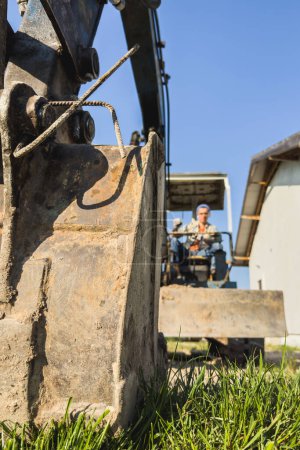 Foto de Joven operando su vieja excavadora durante su trabajo en un sitio de construcción. - Imagen libre de derechos