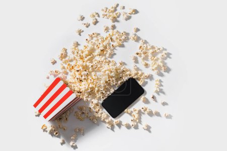 Téléchargez les photos : Seau popcorn classique et smartphone avec écran blanc sur fond blanc. - en image libre de droit