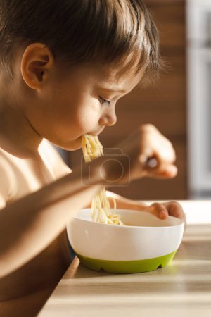 Photo for Cute toddler boy eating his favorite food - Spaghetti. - Royalty Free Image