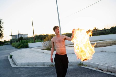 Foto de Joven adulto pirómano quemándose la camisa en la calle - Imagen libre de derechos