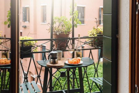Téléchargez les photos : Nature morte de la casserole Moka, tasse de café, abricots et bouteille de vin blanc sur une petite table au balcon - en image libre de droit