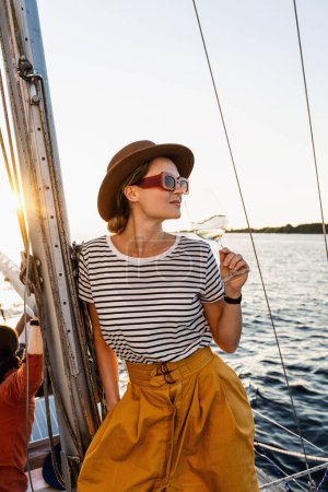 Photo for Attractive woman drinking wine and relaxing on sailboat during sailing in sea. - Royalty Free Image