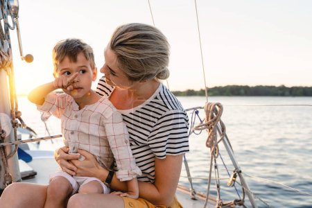 Foto de Joven madre atractiva con su adorable hijo pequeño navegando en el mar en velero - Imagen libre de derechos
