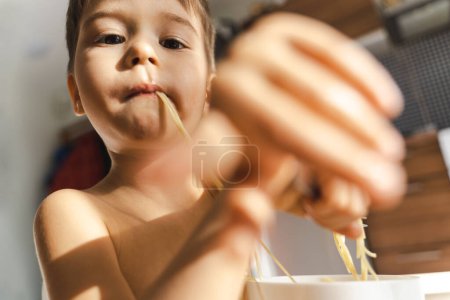 Téléchargez les photos : Bébé mignon garçon manger sa nourriture préférée - Spaghetti. - en image libre de droit