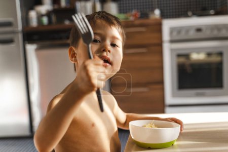 Téléchargez les photos : Bébé mignon garçon manger sa nourriture préférée - Spaghetti. - en image libre de droit