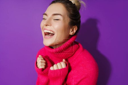 Foto de Retrato de primer plano de gran angular de mujer alegre que usa suéter de cuello de polo caliente sobre fondo púrpura - Imagen libre de derechos