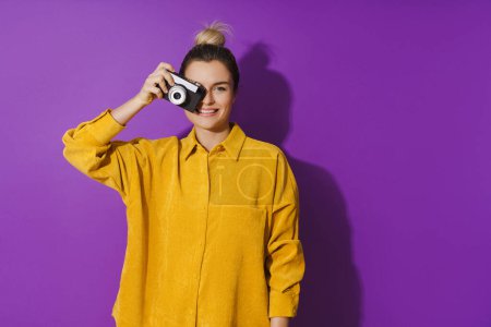 Téléchargez les photos : Portrait de jeune fille gaie avec appareil photo de film sur fond violet - en image libre de droit