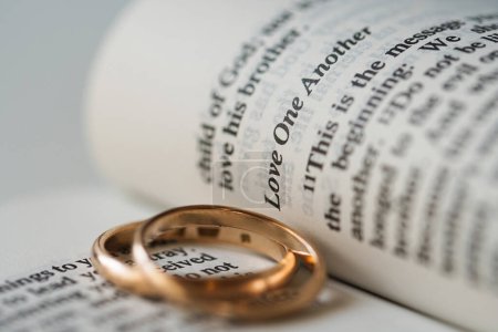Téléchargez les photos : Gros plan de deux alliances dorées et pages ouvertes de la bible sainte représente le concept de mariage et l'amour entre deux chrétiens - en image libre de droit