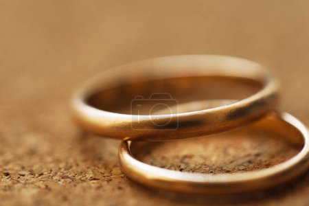 Foto de Macro de dos anillos de boda sobre un fondo de mesa de corcho con DOF poco profundo - Imagen libre de derechos