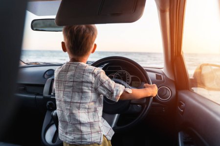 Téléchargez les photos : Petit garçon mignon jouant en voiture et agissant comme un vrai conducteur adulte. - en image libre de droit