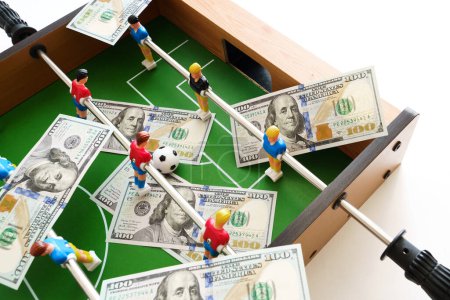 Foto de Juego de futbolín con billetes de dólar esparcidos a su alrededor, aludiendo a un concepto de apuesta y victoria - Imagen libre de derechos