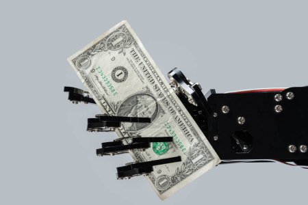 Téléchargez les photos : Une vraie main robotisée avec un billet d'un dollar. Concepts d'investissement dans la technologie de l'intelligence artificielle ou de remplacement d'emplois par l'IA. - en image libre de droit