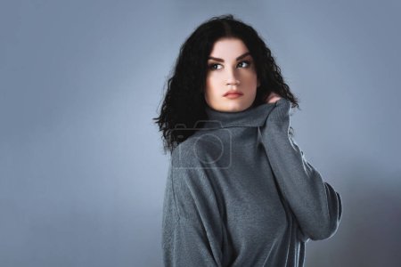 Téléchargez les photos : Portrait studio d'une jeune femme élégante portant un pull à col roulé. - en image libre de droit