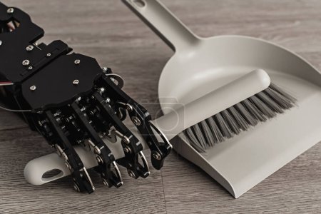 Téléchargez les photos : Robotique main habilement à l'aide d'une pelle à poussière et une brosse pour balayer le sol. - en image libre de droit