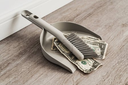 Photo for Dustpan and brush alongside scattered one-dollar bills on the floor. - Royalty Free Image