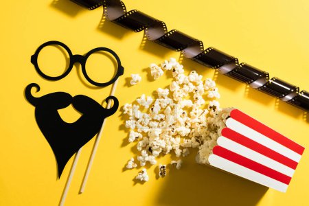 Photo for Popcorn bucket and photo booth prop for movie party on yellow background. - Royalty Free Image