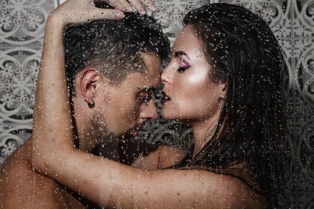 Portrait of beautiful and sensual couple captured through wet glass