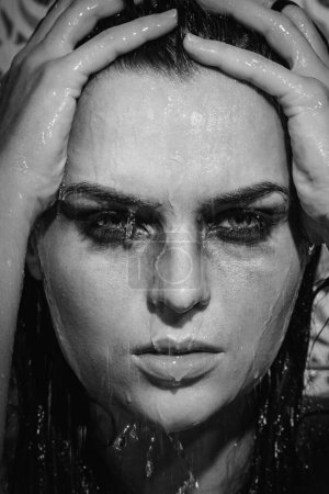 Photo for Monochrome portrait of sad and wet woman with smudged makeup on her face under the shower - Royalty Free Image