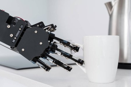 Foto de Mano robot real y taza de café blanco. Concepto de automatización robótica de procesos. - Imagen libre de derechos
