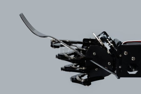 Téléchargez les photos : Une vraie main de robot avec une fourchette. Concept de développement de l'IA et automatisation robotique des processus. - en image libre de droit