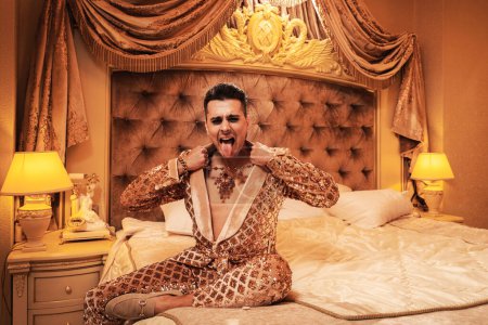 Téléchargez les photos : Homme riche et excentrique vêtu d'un costume doré chatoyant dans une suite royale et luxueuse. - en image libre de droit