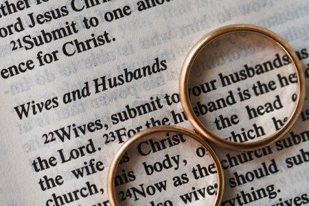 Photo for Closeup of two golden wedding rings and opened pages of holy bible represents the concept of marriage and the love between two Christians - Royalty Free Image