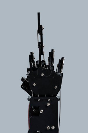 Téléchargez les photos : Véritable main robotique donnant le majeur sur fond gris. Concepts de la prise de contrôle de l'IA et singularité technologique. - en image libre de droit