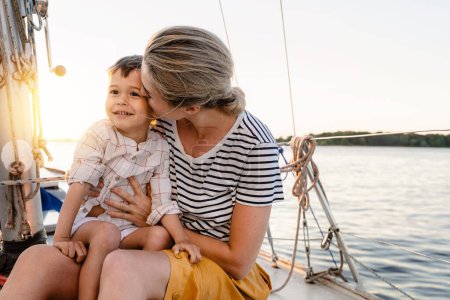 Téléchargez les photos : Jeune belle mère avec son adorable fils tout-petit naviguant en mer sur voilier - en image libre de droit